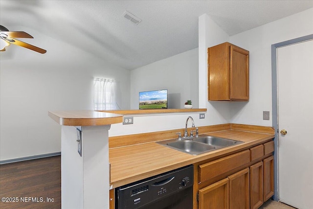 kitchen with brown cabinetry, a peninsula, a sink, vaulted ceiling, and black dishwasher