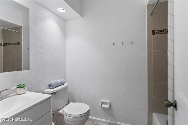 bathroom with vanity, toilet, and a textured wall