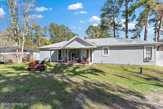 rear view of house featuring fence, a lawn, and metal roof