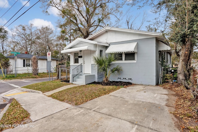 bungalow-style home with crawl space, concrete block siding, and fence