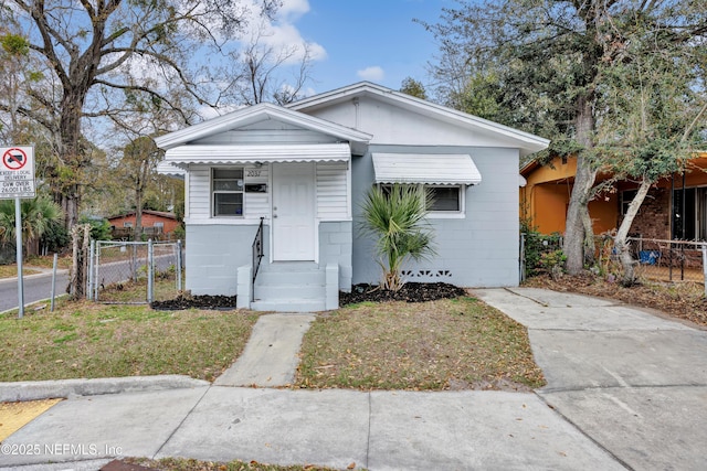 view of front facade with a front yard, concrete block siding, fence, and a gate