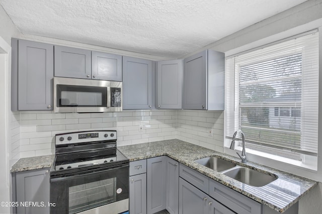 kitchen with a sink, stainless steel microwave, gray cabinets, and electric stove