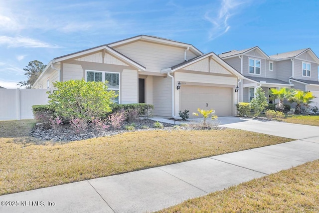 view of front of property featuring an attached garage, fence, concrete driveway, and a front yard