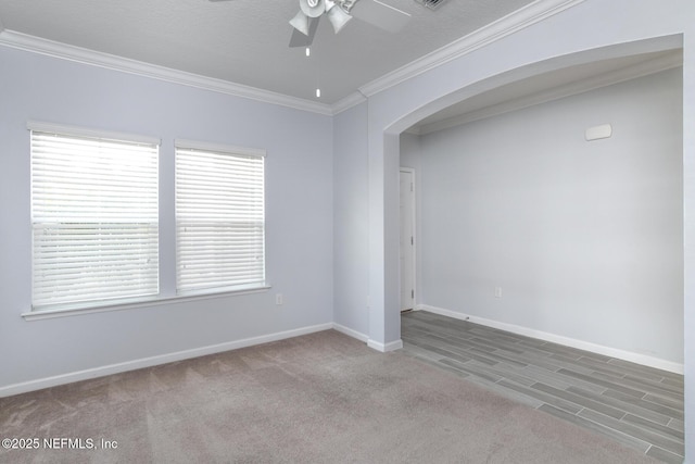 unfurnished room with baseboards, arched walkways, a ceiling fan, ornamental molding, and carpet floors