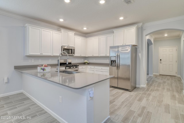 kitchen with arched walkways, appliances with stainless steel finishes, wood finish floors, and white cabinets