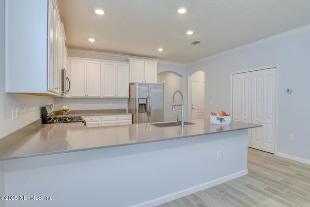 kitchen with appliances with stainless steel finishes, arched walkways, a sink, and ornamental molding