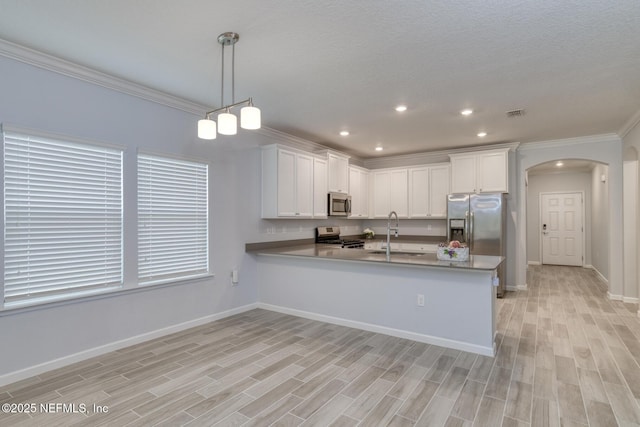 kitchen with arched walkways, stainless steel appliances, light wood-type flooring, and a sink