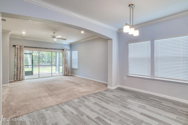 spare room featuring baseboards, arched walkways, ornamental molding, and ceiling fan with notable chandelier