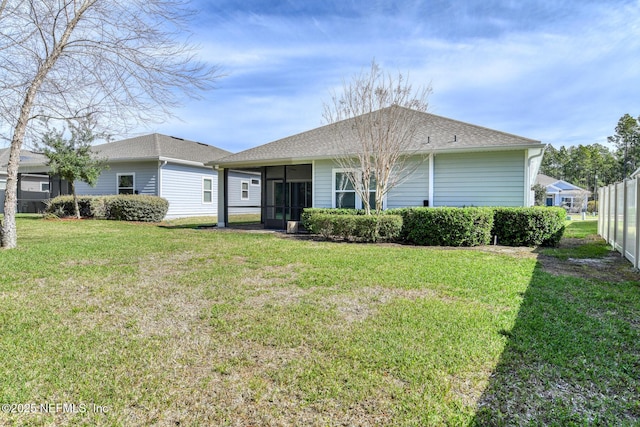 view of front of house featuring a front lawn, roof with shingles, fence, and a sunroom