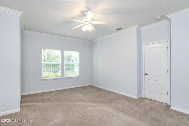 spare room featuring carpet, crown molding, visible vents, a ceiling fan, and baseboards