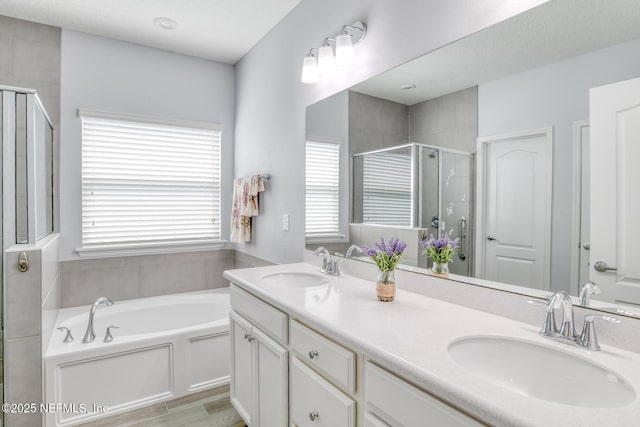 full bath with a garden tub, double vanity, a stall shower, and a sink