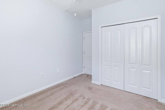 unfurnished bedroom featuring a closet, carpet, visible vents, and baseboards