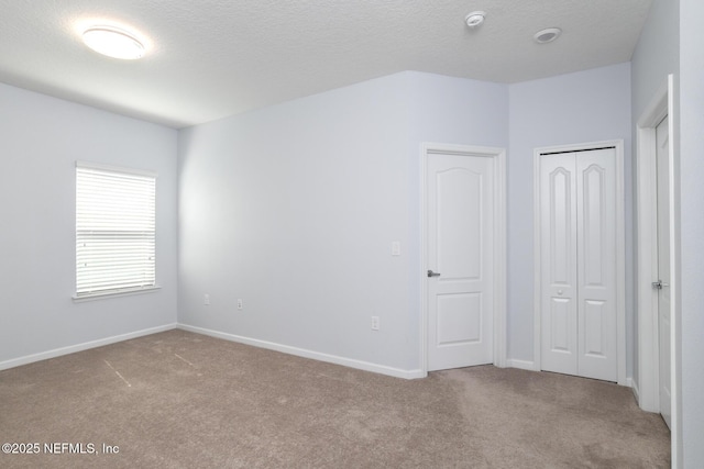 unfurnished bedroom featuring carpet floors, a closet, baseboards, and a textured ceiling