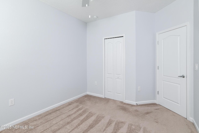 unfurnished bedroom with carpet, baseboards, ceiling fan, and a closet