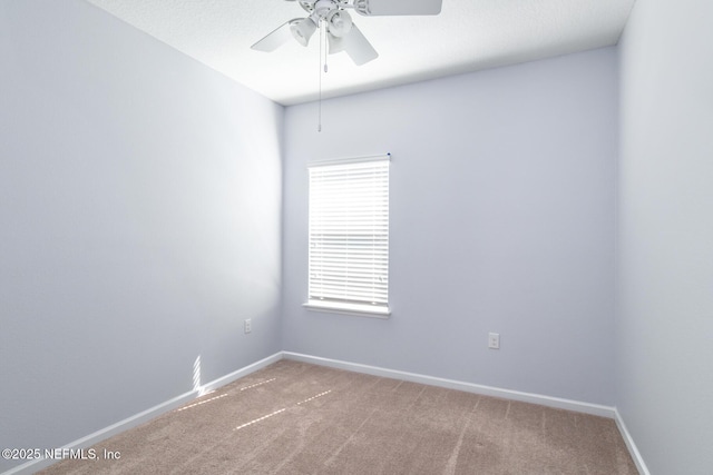 carpeted empty room featuring a ceiling fan and baseboards