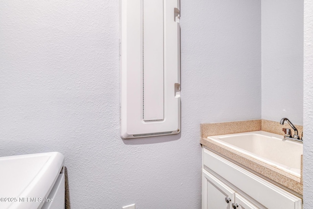 bathroom featuring a textured wall and vanity