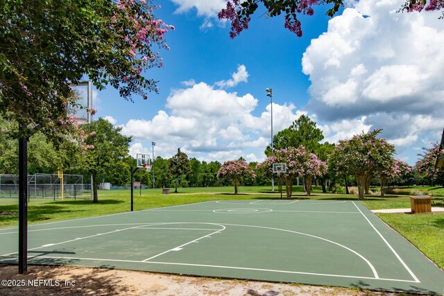 view of basketball court featuring community basketball court, a lawn, and fence