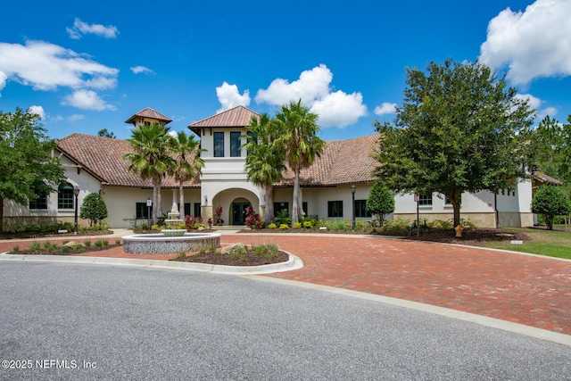 mediterranean / spanish-style house featuring decorative driveway, a tiled roof, and stucco siding