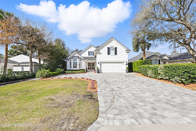 view of front of home with stucco siding, a front lawn, decorative driveway, and a garage