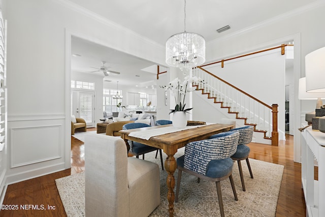 dining room featuring wood finished floors, ornamental molding, and wainscoting