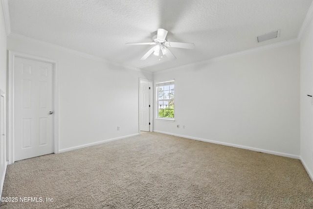 spare room featuring visible vents, ornamental molding, carpet floors, a textured ceiling, and a ceiling fan