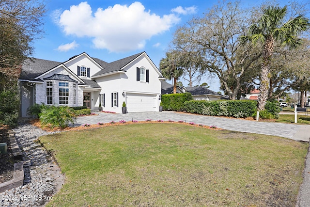 view of front of property with stucco siding, a front lawn, decorative driveway, roof with shingles, and a garage