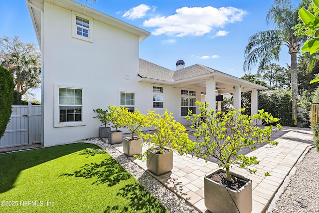 rear view of property featuring a ceiling fan, a patio area, fence, and stucco siding