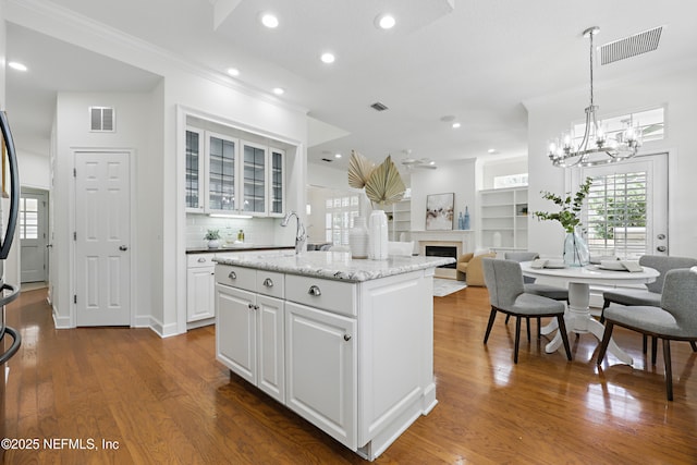 kitchen with visible vents, dark wood-type flooring, a fireplace, and crown molding