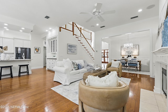 living area featuring hardwood / wood-style floors, stairway, visible vents, and ornamental molding