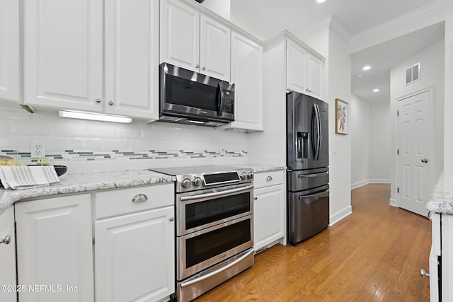 kitchen with visible vents, backsplash, appliances with stainless steel finishes, and white cabinetry