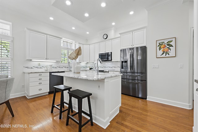 kitchen featuring tasteful backsplash, light wood-type flooring, dishwashing machine, stainless steel refrigerator with ice dispenser, and white cabinetry