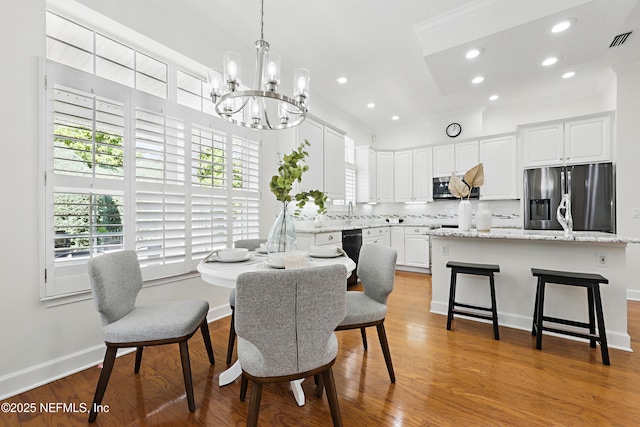 dining room featuring a notable chandelier, visible vents, recessed lighting, and wood finished floors