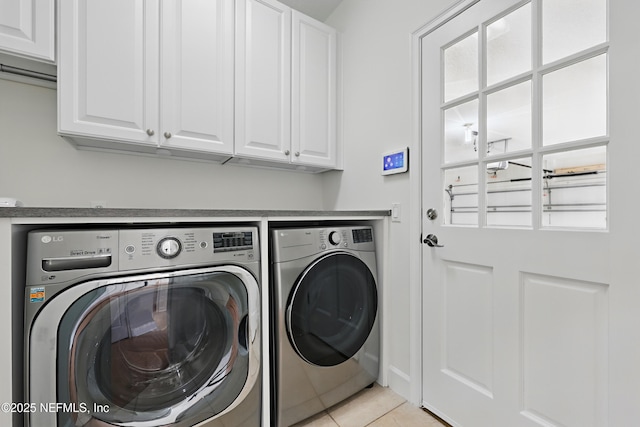 laundry room with light tile patterned floors, cabinet space, and washer and clothes dryer