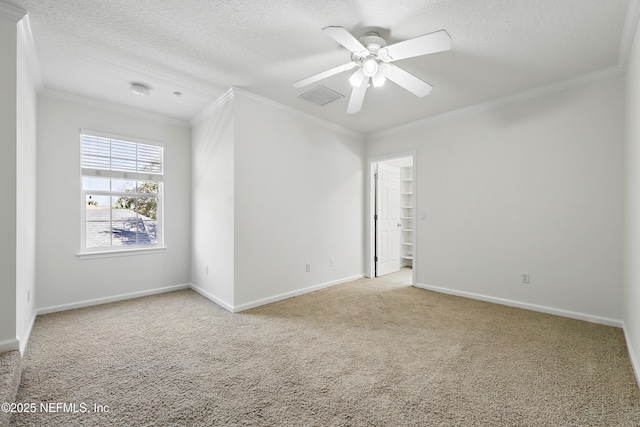 carpeted spare room featuring a textured ceiling, a ceiling fan, baseboards, and ornamental molding