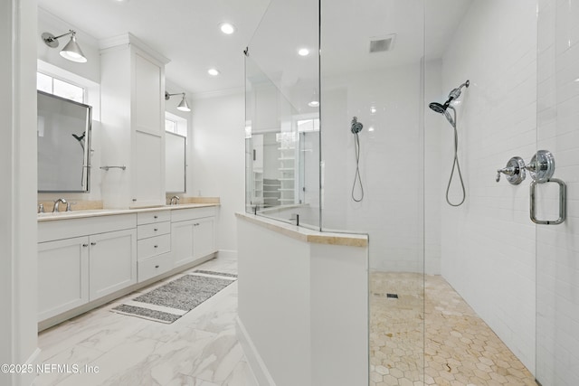 bathroom featuring a sink, double vanity, marble finish floor, and walk in shower