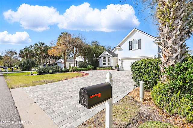 view of front of house featuring stucco siding, a front lawn, decorative driveway, and a garage