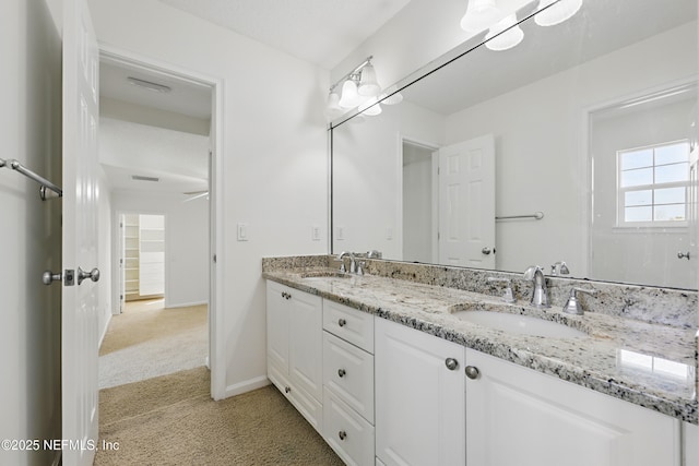 full bath featuring a sink, visible vents, baseboards, and double vanity