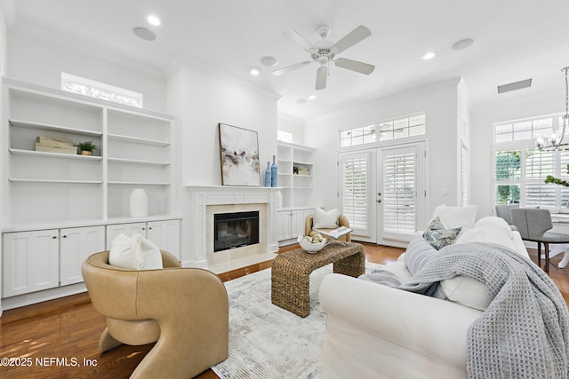 living room featuring dark wood-style floors, visible vents, a wealth of natural light, and ornamental molding