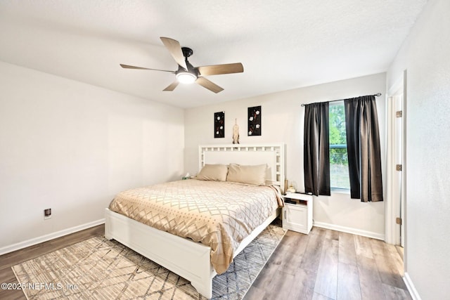 bedroom featuring ceiling fan, light wood-style flooring, and baseboards