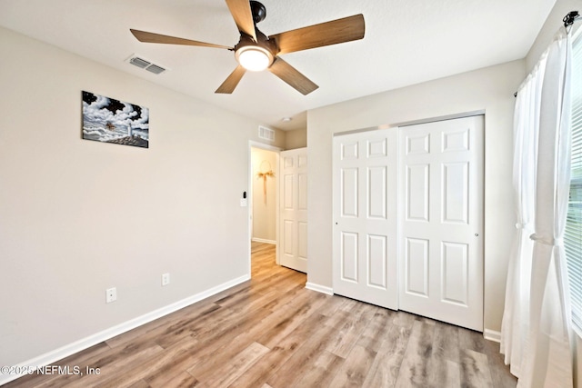 unfurnished bedroom with a closet, visible vents, ceiling fan, light wood-type flooring, and baseboards