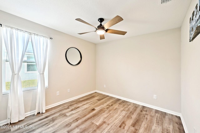 spare room with a ceiling fan, light wood-type flooring, and baseboards