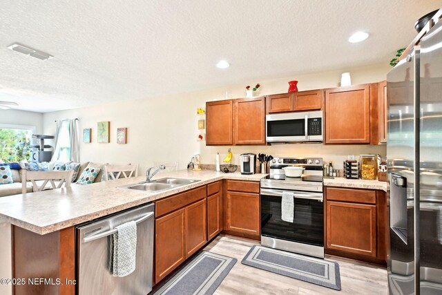 kitchen featuring stainless steel appliances, a peninsula, a sink, visible vents, and light countertops