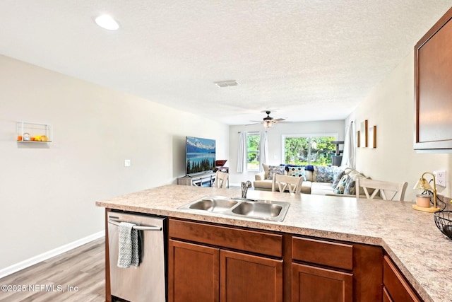 kitchen featuring a sink, open floor plan, light countertops, stainless steel dishwasher, and brown cabinets