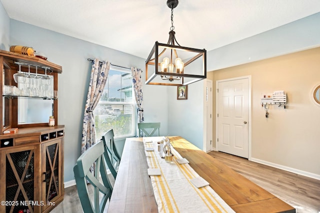 dining room featuring an inviting chandelier, wood finished floors, and baseboards