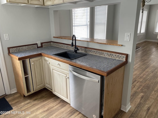 kitchen featuring a sink, light wood-style floors, dark countertops, and dishwasher