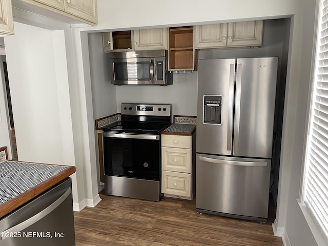 kitchen featuring open shelves, stainless steel appliances, dark wood-type flooring, cream cabinetry, and dark countertops