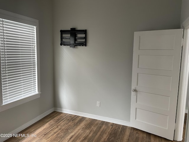 unfurnished room featuring baseboards and dark wood finished floors