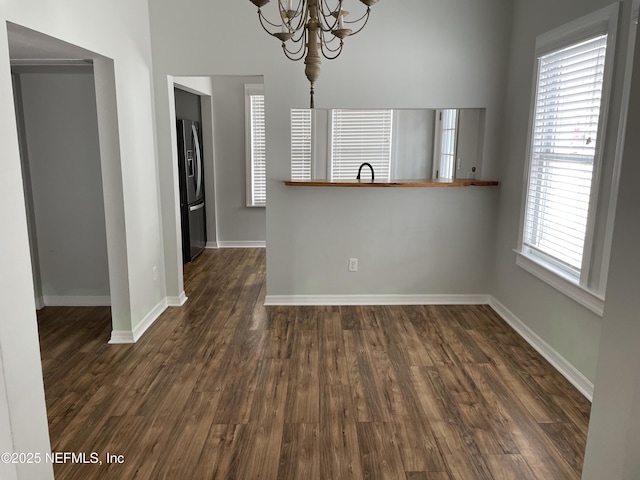 interior space featuring baseboards, dark wood-type flooring, and an inviting chandelier