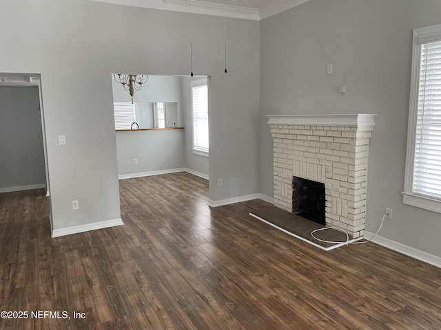 unfurnished living room with a brick fireplace, crown molding, baseboards, and wood finished floors