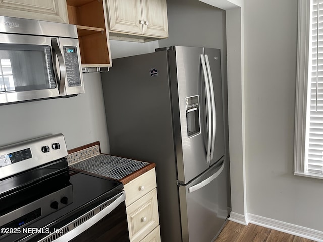 kitchen with dark countertops, baseboards, wood finished floors, stainless steel appliances, and open shelves